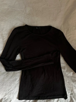 Svart långärmad topp Gina Tricot - En enkel och stilren svart långärmad topp från Gina Tricot. Tillverkad i mjuk bomull med rund halsringning och figurnära passform. 
