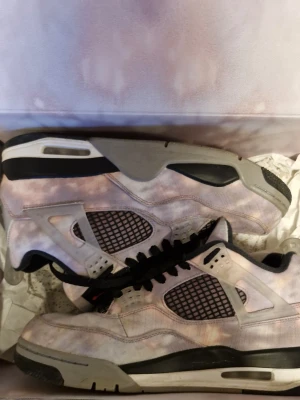 Nike Air Jordan 4 Retro zen master - Unika Nike Air Jordan 4 Retro sneakers med tie-dye mönster i lila, rosa och vitt. Skorna har svarta detaljer, meshpaneler och klassisk Jumpman-logga i orange på plösen. Snygg siluett med grå och svart sula samt svarta skosnören. Rosa snören följer med