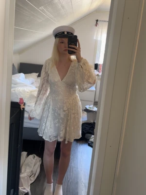 Studentklänning / vit klänning - Vit miniklänning med broderier på tyget. Har en öppen rygg med två knyten och dragkedja baktill. Supersöt till studenten. Storlek 34 men passar mer som en 36. Lappen sitter kvar och den är endast testad, nypris 699🩷