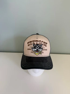 Beige och mörkblå Stetson keps - Tja! Jag säljer nu denna Stetson keps då den aldrig använts sedan jag köpte den ny från Hatstore. Hör av er vid frågor! 😊