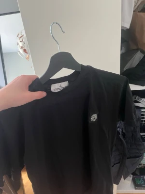Svart Stone Island t-shirt - Säljer en svart t-shirt från Stone Island med klassisk logga på bröstet. En stilren T-shirt perfekt nu inför sommaren. Storlek S ( nypris oklart )