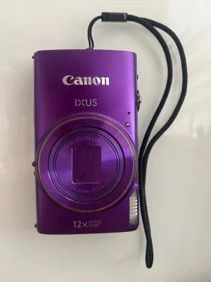 Lila Canon IXUS 285 HS - Canon IXUS 285 HS 20,2MP Kompaktkamera - får till riktigt fina och skarpa instagrambilder. Billigare alternativ för G7x - kommer med batteri, minneskort, laddare och fodral - köpt från USA, finns ej inom EUs gränser