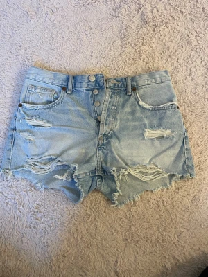 Ljusblåa slitna jeansshorts från Zara - Säljer ett par ljusblå jeansshorts från Zara. Säljs på grund av att de inte kommer till användning💗