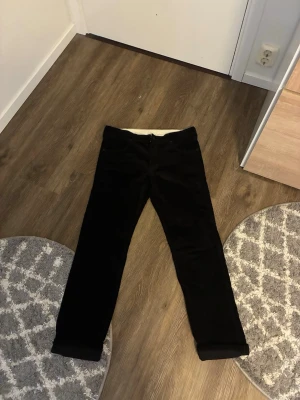 Svarta manchesterbyxor Wrangler - Säljer ett par svarta manchesterbyxor från Wrangler med klassisk rak passform. Byxorna har fem fickor, bälteshällor och dragkedjegylf. Materialet är mjuk manchester som ger en retro och stilren look.