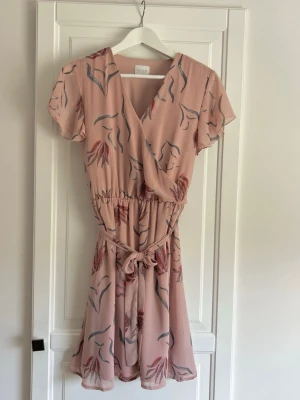 Klänning - Vila  - Rosa blommönstrad klänning från Vila. Skärp i midjan. Storlek 34. I mycket fint skick, endast använd ett fåtal gånger 🌸 Längd - ca 89cm