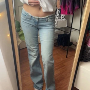 Ljusblå bootcut jeans med låg midja - Säljer ett par ljusblå jeans med bootcut och låg midja. Jeansen har klassisk femficksdesign och dragkedja med knapp. Perfekta för dig som gillar en avslappnad och trendig look.