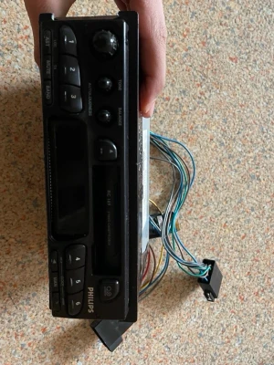 Philips bilstereo med kassett - Säljer en svart bilstereo från Philips med kassettspelare och radio. Modellen har flera knappar för radiokanaler, volym- och balansreglage samt uttag för antenn och högtalare. Perfekt för dig som gillar retroprylar till bilen.