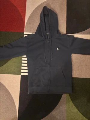 Mörkblå hoodie från Polo Ralph Lauren - Säljer en ralph lauren zip up. Säljer den eftersom att den inte passar mig.