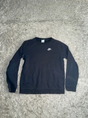 Svart crewneck sweatshirt från Nike - En svart crewneck sweatshirt från Nike med klassisk vit logga på bröstet. Tröjan har rund halsringning, långa ärmar och ribbade muddar vid ärmslut och nederkant. Perfekt för en avslappnad och sportig stil. För fler frågor/bilder skriv privat.