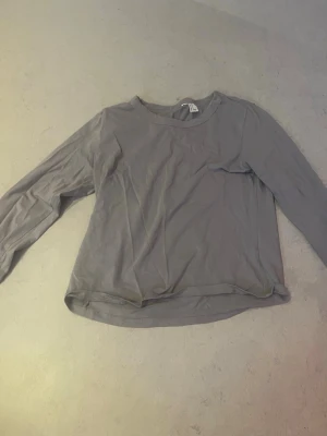 Grå långärmad topp - En enkel och stilren grå långärmad topp med rund halsringning. Tillverkad i mjukt bomullsmaterial som känns skönt mot huden. Perfekt basplagg att matcha med olika outfits. Andvänt ganska mycket men ändå har den bra sick 