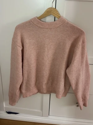 Ljusrosa stickad tröja - Mysig ljusrosa stickad tröja med rund halsringning och ribbade muddar vid ärmslut och nederkant. Tröjan har en enkel och stilren design, perfekt för lager på lager och passar till många olika outfits. Materialet ser mjukt och bekvämt ut☺️