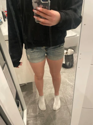Blå lågmidjade denimshorts med slitningar - Säljer ett par klassiska blå lågmidjade jeansshorts i denim med slitna detaljer och upprullade benslut. Säljer då de tyvvär har blivit för små för mig. Shortsen har normal passform, bälteshällor och fem fickor. Perfekta för varma dagar och enkel att matcha med olika toppar. Shortsen är köpta utomlands men från märket double burger. Midjemåttet är 76 cm dvs ca storlek M men de är väldigt tighta så jag skulle säga att de är ca storlek S. 