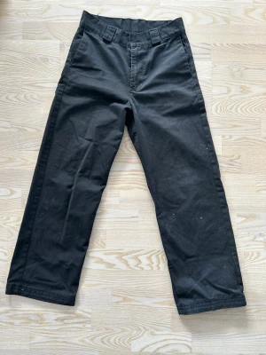 Svarta byxor från sweet sktbs - Säljer ett par svarta byxor från sweet sktbs i rak modell med hög midja och breda hällor. Materialet är kraftigt och slitstarkt, perfekt för en avslappnad streetwear-look. Byxorna har enkel design utan synliga fickor framtill.