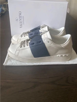 Valentino Garavani open vita marinblå sneakers - Säljer ett par Valentino Garavani Open sneakers. Kommer med dustbag och box. Pertekta för dig som vill ha en clean men lyxig look. Stl 45/46. Innermått ca 28,5-29 cm.