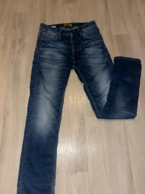 Blå slim fit jeans från Jack&jones  - Snygga blå slim fit jeans med slitningar och tvättade detaljer från Jack&jones 27/32 stolek 