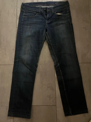 Mörkblå raka jeans från Flirt - Snygga mörkblå jeans från Flirt med raka ben och klassisk femficksmodell. Jeansen har subtila slitningar och kontrastsömmar för en cool look. Tillverkade i bomull med en bekväm passform som passar till det mesta. Storlek 30