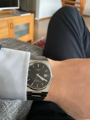Tissot PRX 35mm - Snygg Tissot PRX powermatic 80 i rostfritt stål med svart urtavla och datumvisning. Använder antingen rörelser eller skruv funktionen för att ”ladda” upp klockan. Jag har använt den som en beater i runt 2 år. Det finns en del repor på armbandet som syns på bild två. Den är 35mm till storleken så perfekt till de som har lite smalare handleder. Jag är öppen för prisförslag!