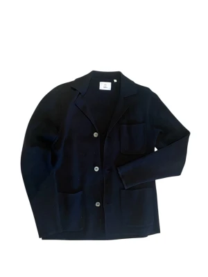 Marinblå overshirt  - Stilren marinblå overshirt från Bläck med tre knappar framtill och tre utanpåliggande fickor. Klassisk krage och mjukt, stickat material som ger en avslappnad men ändå dressad look. Perfekt för dig som vill ha en enkel och snygg kavaj. Har använts max 3 gånger eftersom jag har vuxit som bara den. Säljer till ett mycket bra pris!🤩