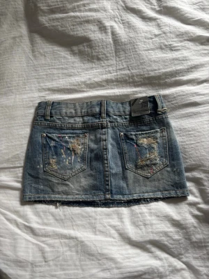 Unik mini kjol - Så fin och unik kjol köpt i Thailand! Dessvärre var den för liten på mig.. bra material och verkar helt oanvänd! Skulle uppskatta storleken till en xs/s då den är ganska tajt över rumpa och höfter men midjemått på ca 38 cm. Lite blåare i verkligheten