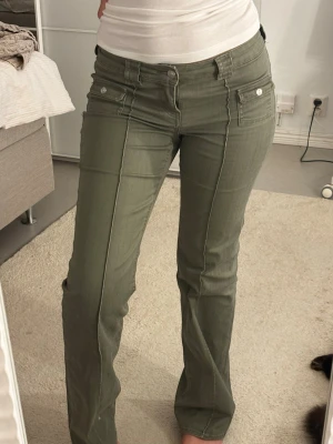 Olivgröna bootcut  - Snygga olivgröna jeans med bootcut passform och dekorativa sömmar framtill. Jeansen har dubbla fickor med lock och knapp framtill. Byxorna är i storlek 38 men passar de med 36💕 från H&M men säljs inte någon mer!