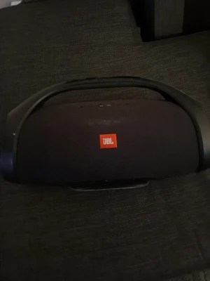 JBL Boombox bärbar högtalare svart - Kraftfull JBL Boombox bärbar högtalare i svart med robust handtag och ikonisk JBL-logga. Högtalaren har rundad form, tydliga knappar på ovansidan och sidor i plast. Perfekt för att ta med sig musiken överallt. Lite smutsigt men funkar felfritt 