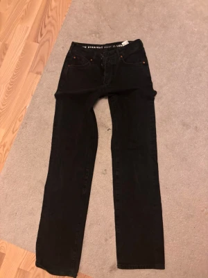 Svarta straight jeans från Levi's - Snygga svarta straight fit jeans med klassisk femficksdesign och knappgylf.