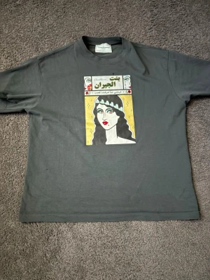 Casablanca t shirt  - Säljer en mörkgrå t-shirt från Creativity London med ett unikt grafiskt tryck framtill i färgerna gul, vit och svart. T-shirten har klassisk passform och korta ärmar. Perfekt för dig som vill sticka ut med en cool design.