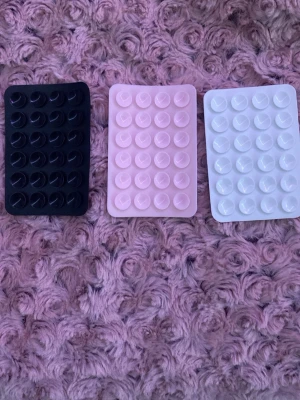 3 st Sugproppar för mobilen - Säljer ett 3-pack sugproppshållare till mobil i svart, rosa och vitt. Perfekt för att fästa mobilen på olika ytor eller använda som stativ.