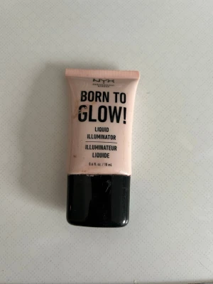 NYX Born To Glow Liquid Highlighter - Halva kvar. NYX Born To Glow Liquid Illuminator i nyansen Sunbeam. En flytande highlighter i en ljusrosa ton med skimrande finish. Kommer i en mjuk tub med svart skruvlock. Perfekt för att ge ansiktet extra lyster och glow.