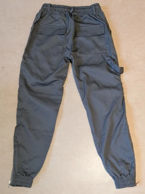 Grå Cargo byxor Pojke  - Grå oanvända cargo byxor. Passar för barn mellan 140-155 cm ungefär. Nytt skick utan prislapp kvar på byxorna och ingen orginal förpackning kvar 
