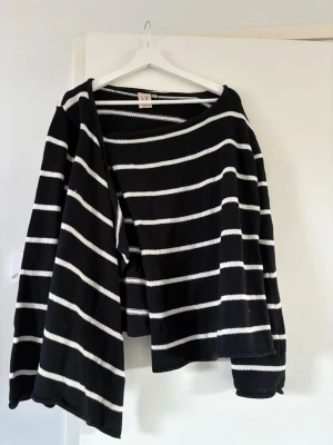 Svartvit randig kofta  - Snygg svart kofta med vita horisontella ränder. Koftan är öppen framtill och har långa ärmar. Stickad i mjukt material och har en enkel, avslappnad passform. Perfekt för lager på lager och enkel att matcha.