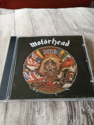 Motörhead 1916 CD-album - Säljer ett CD-album av Motörhead med titeln 1916. Omslaget har bandets logga och flera flaggor i en cirkel runt ett krigstema. Skivan innehåller 11 låtar och ges ut av Epic/Sony Music. Perfekt för dig som gillar klassisk hårdrock.