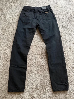 Nudie Jeans Steady Eddie  - Modell: Steady Eddie🪬  Färg: Svart🪬  Storlek: W30 L34 🪬  Mått: W38cm L105cm Benöppning 17cm🪬  Skriv vid minsta fundering!🪬