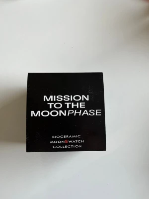 Omega x Swatch MoonSwatch klocka - Säljer en svart Omega x Swatch MoonSwatch från Bioceramic MoonSwatch Collection. Klockan har en rund urtavla med vita detaljer och logga, samt svart armband. Kommer i originalförpackning med manual och certifikat.