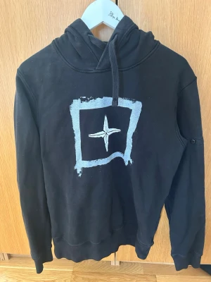 Svart hoodie med Polestar-logga - Snygg svart hoodie från Polestar med stor logga i vitt både fram och bak. Hoodien har huva och ribbade muddar vid ärmar och nederkant. Patch kommer med. 