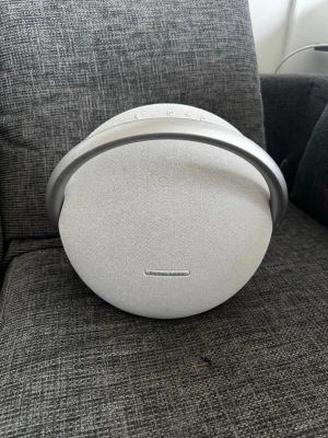 Harman Kardon Onyx Studio vit högtalare - Snygg trådlös högtalare från Harman Kardon i rund design med vit textilfront och silverfärgat handtag. Perfekt för att streama musik via Bluetooth. Stilren och modern look som passar in i alla rum.