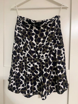 Leopardmönstrad kjol By Malene Birger - Snygg leopardmönstrad kjol från By Malene Birger i svart, beige och vit. Kjolen har en lätt utsvängd form och är tillverkad i ett mjukt, följsamt material som ger en skön känsla. Perfekt för dig som vill sticka ut med ett trendigt mönster.