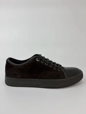 Svarta Lanvin sneakers med mocka och lack - Stilrena svarta sneakers med ovandel i mocka och tåparti i blankt lackmaterial. Skorna har svarta snören, metallöljetter och en svart sula. Perfekta för dig som gillar en clean och modern look med en twist av olika material.