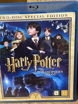 Harry Potter and the Philosopher's Stone Blu-ray - Tvådisc specialutgåva av Harry Potter and the Philosopher's Stone på Blu-ray. Omslaget är blått med gulddetaljer och motiv från filmen. Innehåller både filmen och extramaterial om skapandet av Harry Potters värld. Perfekt för samlare och fans av fantasy.