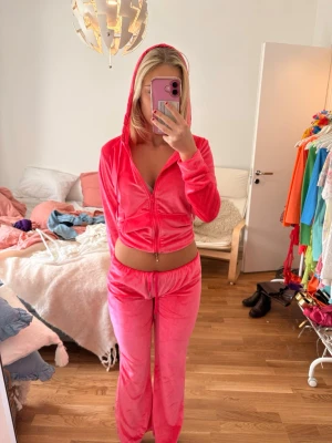 Juicy couture velourset  - Mysigt loungewear-set i rosa velour med zip-hoodie och matchande byxor med resår i midjan. Hoodien har dragkedja och långa ärmar. Perfekt för chill dagar hemma! Säljs som ett par. Innerbensmått 67, midjan Max 43cm.