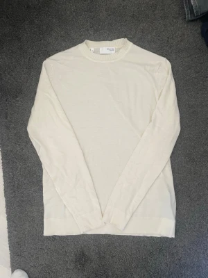 Vit tröja från Selected Homme - Säljer en stilren vit tröja från Selected Homme. Tröjan har rund halsringning, långa ärmar och är tillverkad i ett mjukt och tunt material som passar perfekt till jeans. Enkel och clean design som funkar året runt.