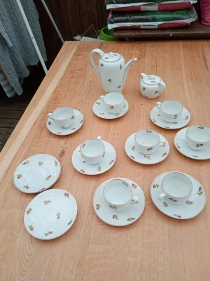 Gammal Kaffeservis i porslin med blommor Bavaria nr 360 - Säljer en klassisk kaffeservis i vitt porslin med små färgglada blommor och guldkant. Setet innehåller kaffekanna, gräddkanna, sex koppar med fat samt extra assietter. Perfekt för fika med vänner eller familj. Åtta koppar med fat samt två extra små fat och ej sex koppar med fat  Se bilder. Någon kopp med liten nagg . Mycket fint skick.