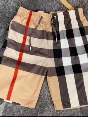 Burberry shorts - Snygga shorts från Burberry med klassiskt rutigt mönster i beige, svart, vitt och rött. Shortsen har snörning i midjan och är perfekta för en trendig och avslappnad stil. Passar dig som gillar att sticka ut med ikoniska mönster.