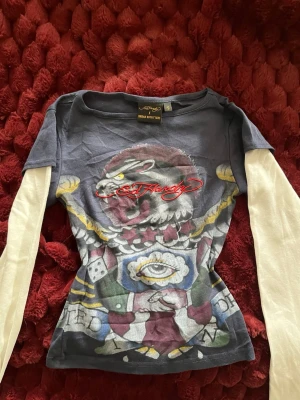 Ed Hardy långärmad topp med tryck - Cool långärmad Ed Hardy topp med vita ärmar och mörkblå kropp. Slim fit och tillverkad i mjuk bomull. Statement-plagg, passar xs-xxs fast det står S på lappen, helt oanvänd 