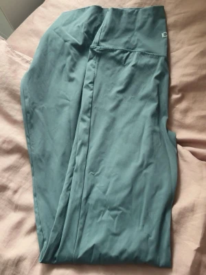 Gröna idrottsbyxor från ICANIWILL - Supersnygga blågröna leggings från ICANIWILL med utsvängda ben och hög midja. Mjukt och stretchigt material som sitter skönt på kroppen. Storlek xs