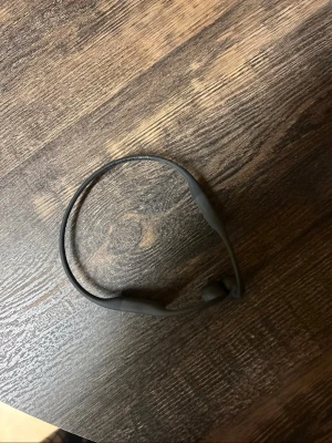 Svarta Aftershokz bone conduction-hörlurar - Säljer ett par svarta Aftershokz trådlösa bone conduction-hörlurar. De har en smidig och flexibel bygel som sitter runt nacken och öronen. Perfekta för dig som vill höra omgivningen samtidigt som du lyssnar på musik eller poddar.