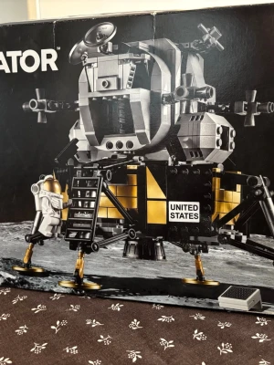 LEGO NASA Apollo 11 Lunar Lander - Byggsats från LEGO som föreställer NASA:s Apollo 11 Lunar Lander. Modellen är detaljerad med svart, guld och silverfärgade klossar, två astronautfigurer och amerikansk flagga. Perfekt för rymdintresserade och samlare av LEGO Creator-serien.Aldrig använt ,oöppnad förpackning.