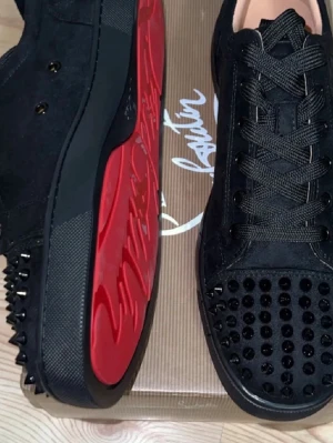 Svarta Louboutin sneakers med nitar - Säljer ett par svarta sneakers från Christian Louboutin i mocka med svarta nitar på tån och hälen. Skorna har klassisk röd sula, svarta skosnören och en låg silhuett. Perfekta för dig som vill sticka ut med en edgy och lyxig stil. Priset kan vi diskutera dm