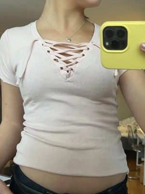 Ljusrosa topp med snörning - Supersöt ljusrosa topp med snörning, perfekt att styla med jeans eller kjol🩷🩷