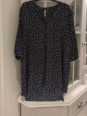 Svartprickig blus från Joythi - Mönstrad blus i svart med vita prickar från Joythi. Blusen har en lös passform, rund halsringning och trekvartsärm. Perfekt för dig som gillar en avslappnad men ändå trendig stil. Materialet känns lätt och luftigt.